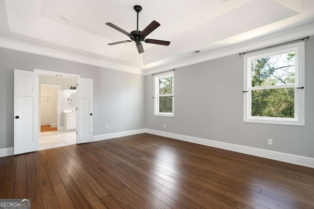 unfurnished bedroom featuring ceiling fan, ensuite bath, dark hardwood / wood-style flooring, and a raised ceiling