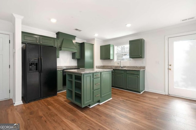 kitchen with a center island, custom exhaust hood, sink, black fridge, and green cabinetry