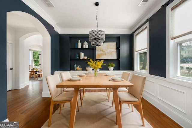 dining room with ornamental molding, wood-type flooring, and a notable chandelier