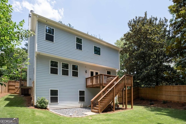 rear view of property featuring a wooden deck and a lawn