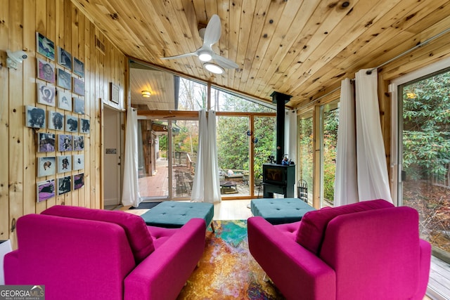 sunroom / solarium featuring wooden ceiling, lofted ceiling, a wood stove, and ceiling fan