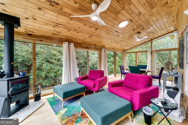 sunroom with a wood stove, a wealth of natural light, wood ceiling, and vaulted ceiling