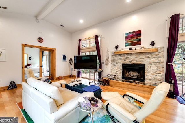 living room with a wealth of natural light, vaulted ceiling with beams, hardwood / wood-style floors, and a fireplace