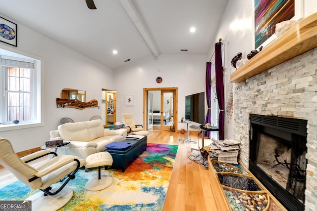 living room featuring vaulted ceiling with beams, a fireplace, and wood-type flooring