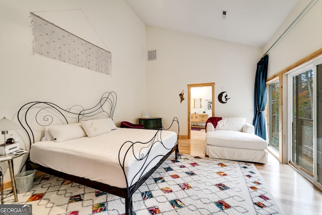 bedroom featuring light hardwood / wood-style floors, multiple windows, high vaulted ceiling, and access to outside