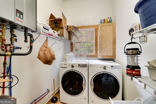 clothes washing area with washer and clothes dryer, water heater, and cabinets