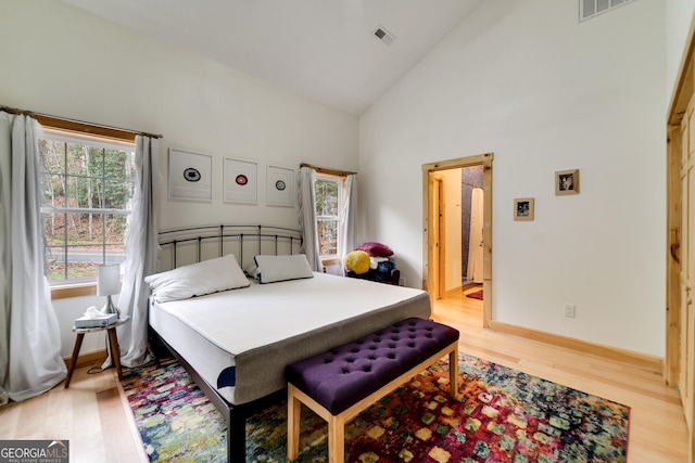 bedroom with high vaulted ceiling and wood-type flooring