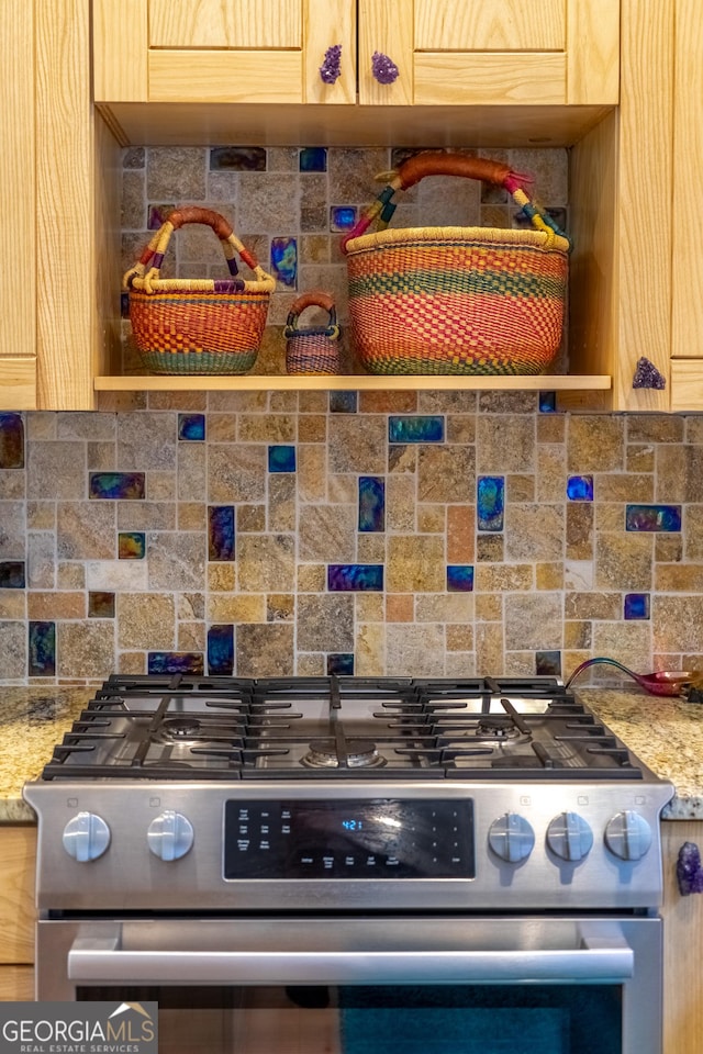 kitchen featuring light stone counters, stainless steel range with gas cooktop, light brown cabinets, and decorative backsplash