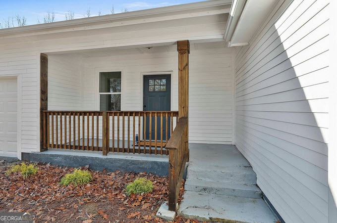 view of exterior entry with covered porch and a garage