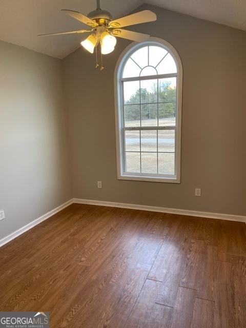 spare room featuring ceiling fan, dark hardwood / wood-style flooring, and lofted ceiling