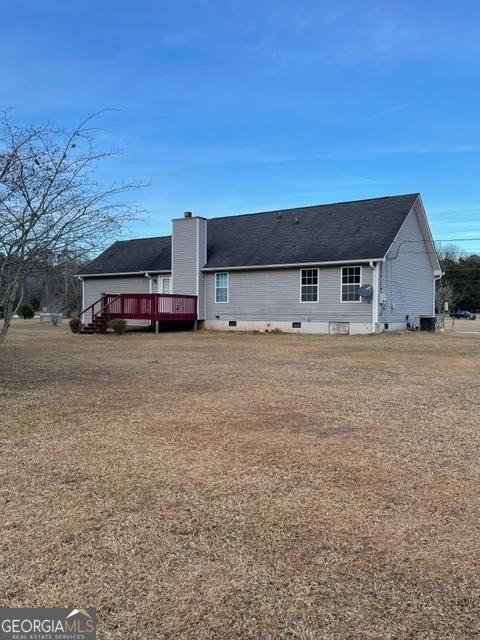 back of property with a deck and a yard