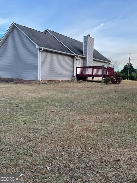 view of side of property featuring a wooden deck and a yard