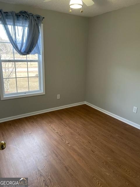 unfurnished room featuring dark wood-type flooring, ceiling fan, and a textured ceiling