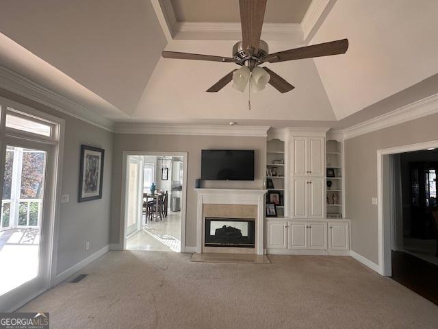 unfurnished living room featuring light carpet, ceiling fan, a multi sided fireplace, and a raised ceiling