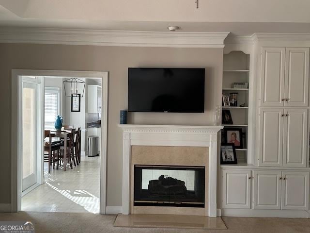 living room with light carpet, a notable chandelier, a multi sided fireplace, ornamental molding, and built in shelves