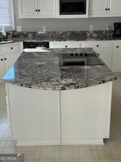 kitchen featuring light tile patterned floors, dark stone counters, black electric cooktop, and white cabinetry