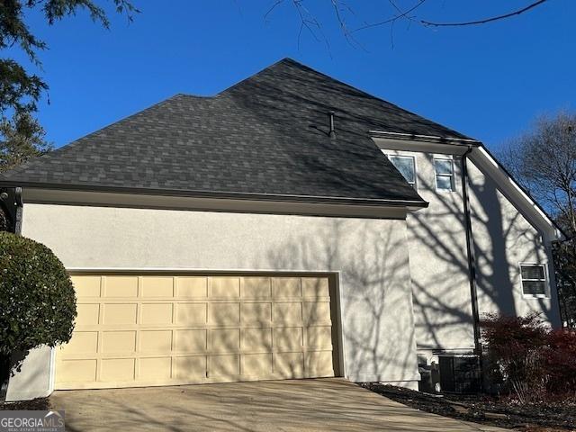 view of side of home featuring a garage and cooling unit