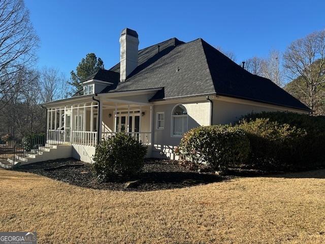 back of property with a sunroom and a yard