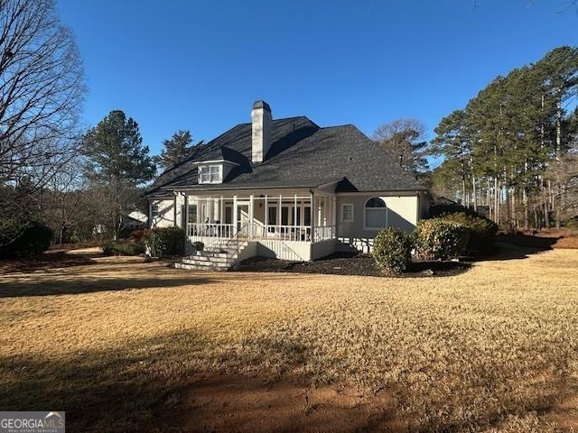 rear view of house featuring a lawn and a sunroom