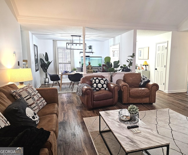 living room with a textured ceiling, dark hardwood / wood-style flooring, ornamental molding, and an inviting chandelier