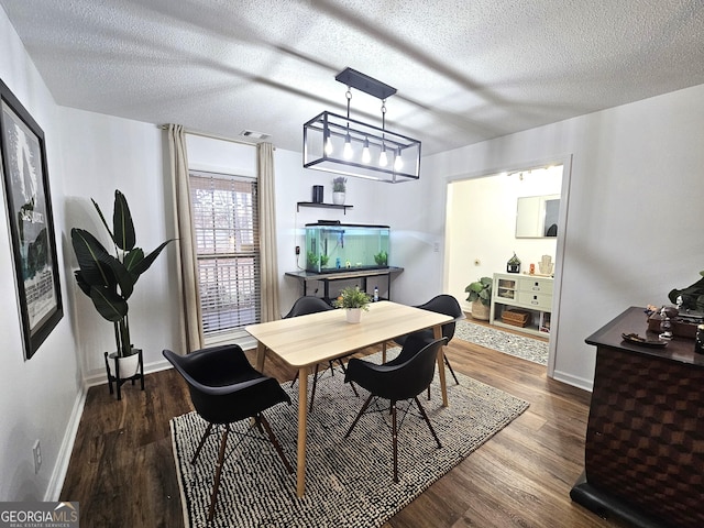 dining space with a textured ceiling and dark hardwood / wood-style flooring