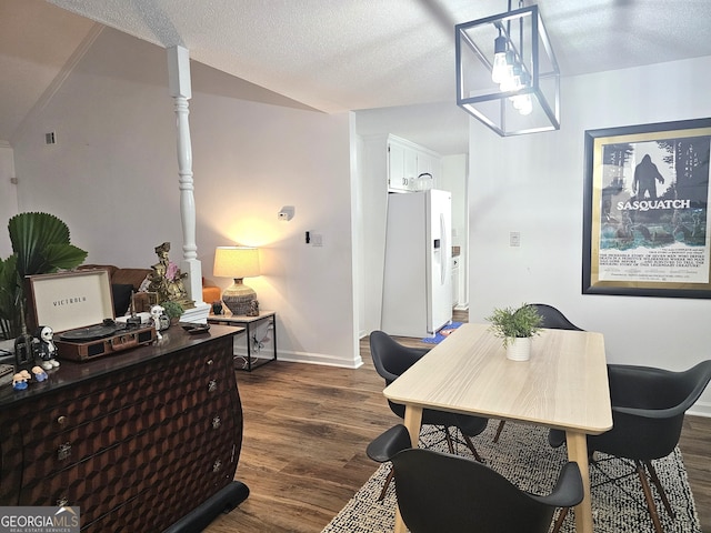 dining space featuring vaulted ceiling, a textured ceiling, and dark hardwood / wood-style flooring