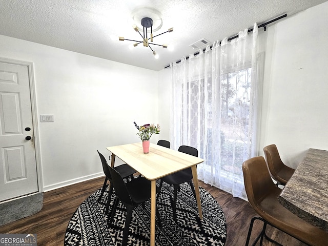 dining space featuring dark wood-type flooring, a textured ceiling, and a notable chandelier