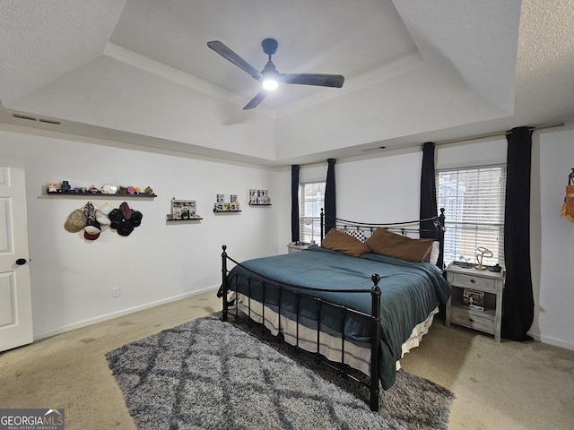 bedroom with ceiling fan, carpet, a raised ceiling, and a textured ceiling