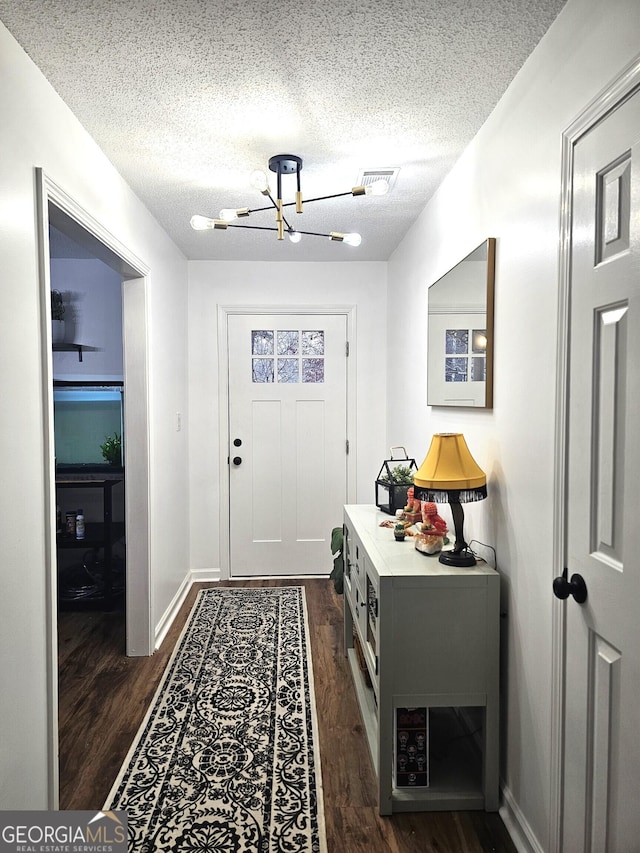 entryway featuring a chandelier, a textured ceiling, and dark hardwood / wood-style flooring