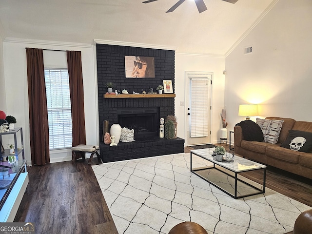 living room featuring hardwood / wood-style floors, crown molding, a fireplace, ceiling fan, and lofted ceiling