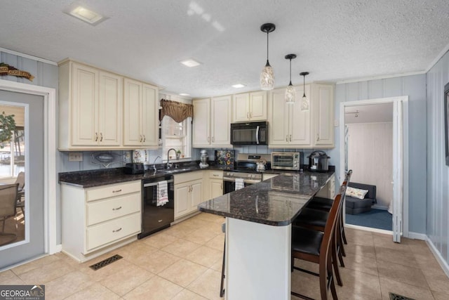 kitchen with a textured ceiling, a breakfast bar area, hanging light fixtures, and black appliances