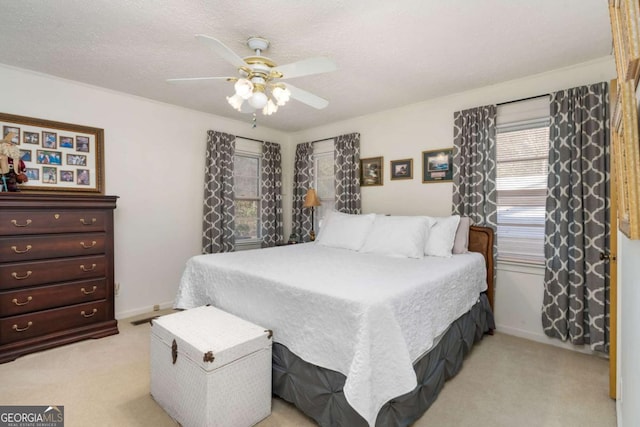 bedroom with a textured ceiling, ceiling fan, and light carpet