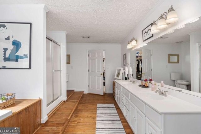 bathroom with a shower with shower door, a textured ceiling, hardwood / wood-style flooring, and vanity