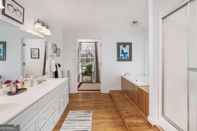 bathroom with a textured ceiling, vanity, hardwood / wood-style floors, and separate shower and tub