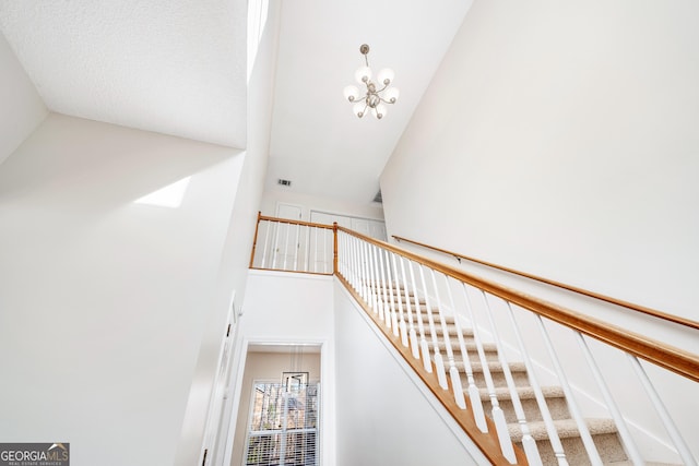 staircase featuring a chandelier and high vaulted ceiling