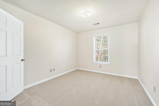 carpeted empty room featuring a textured ceiling