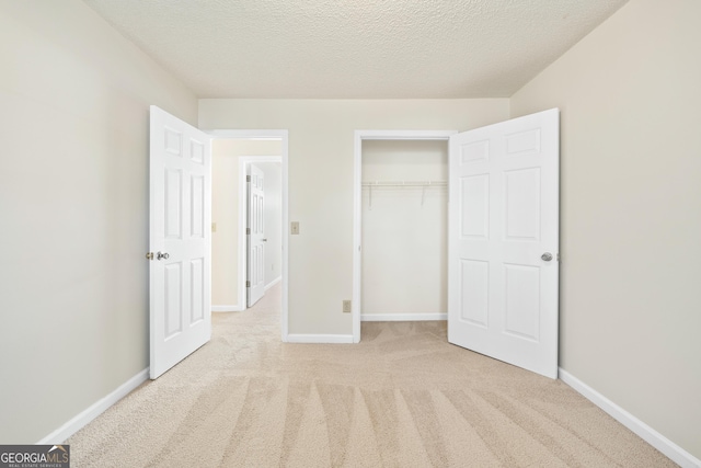 unfurnished bedroom featuring light colored carpet, a closet, and a textured ceiling