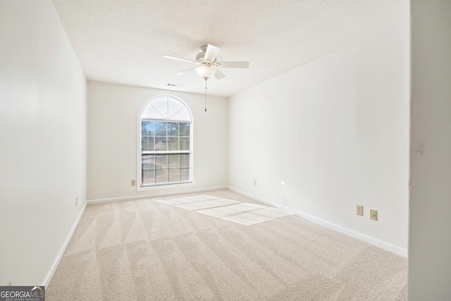 spare room with a textured ceiling, ceiling fan, and light colored carpet