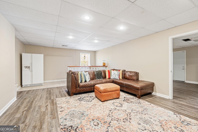 living room with light hardwood / wood-style floors and a drop ceiling