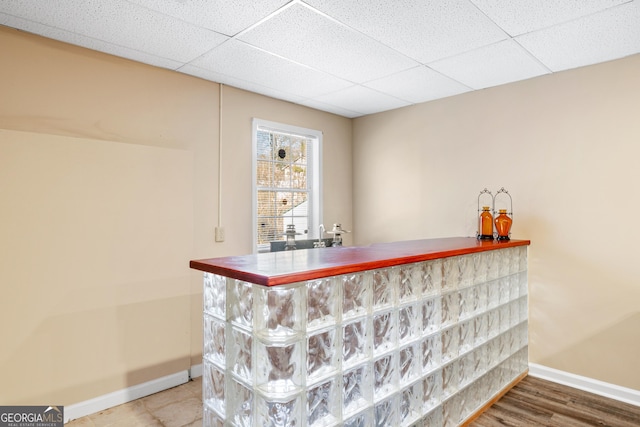 bar with wood-type flooring and a drop ceiling