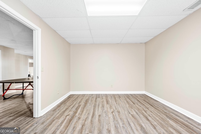 empty room with a paneled ceiling and light hardwood / wood-style floors