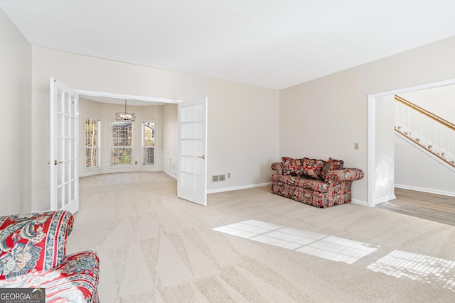 living area featuring a chandelier, light carpet, and french doors