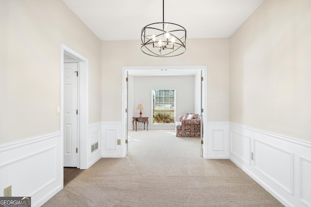 hall featuring light colored carpet and a notable chandelier