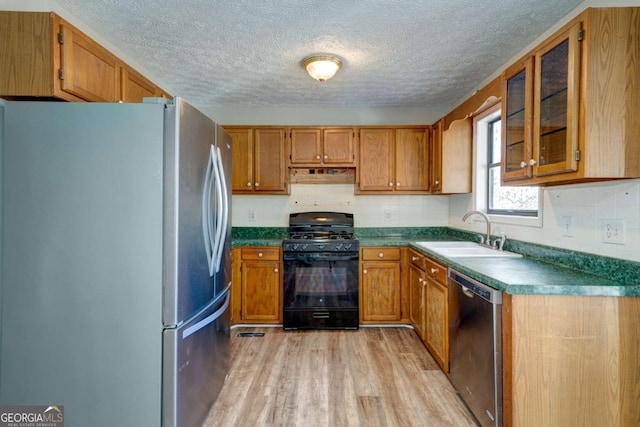 kitchen featuring a textured ceiling, sink, stainless steel appliances, and light hardwood / wood-style flooring