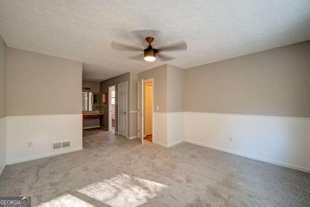 spare room featuring ceiling fan, light carpet, and a textured ceiling