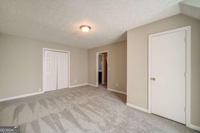 unfurnished bedroom with light carpet, a closet, and a textured ceiling