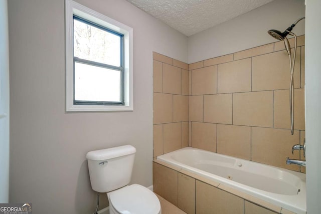 bathroom with a textured ceiling, toilet, and tiled shower / bath combo