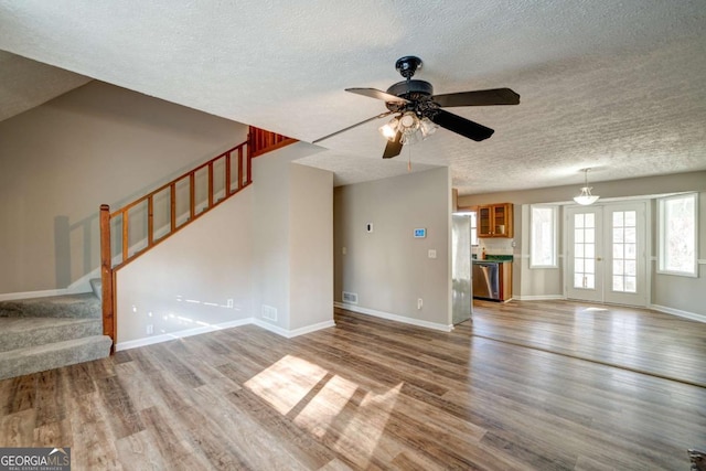 unfurnished living room with ceiling fan, wood-type flooring, and french doors