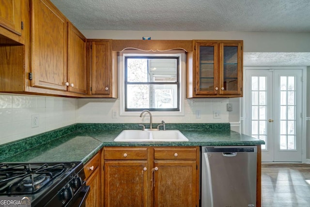 kitchen with plenty of natural light, french doors, a textured ceiling, stainless steel dishwasher, and sink