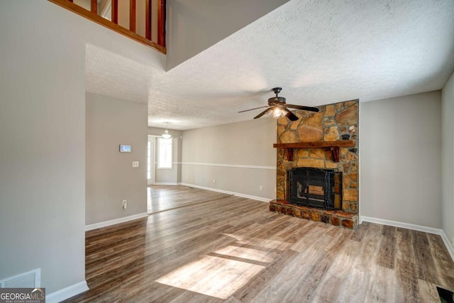 unfurnished living room featuring a textured ceiling, ceiling fan, a fireplace, and hardwood / wood-style floors